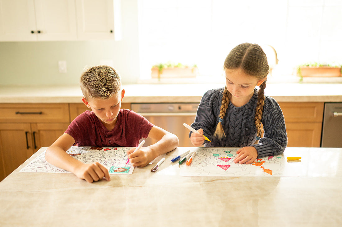 Children drawing on a reusable coloring mat